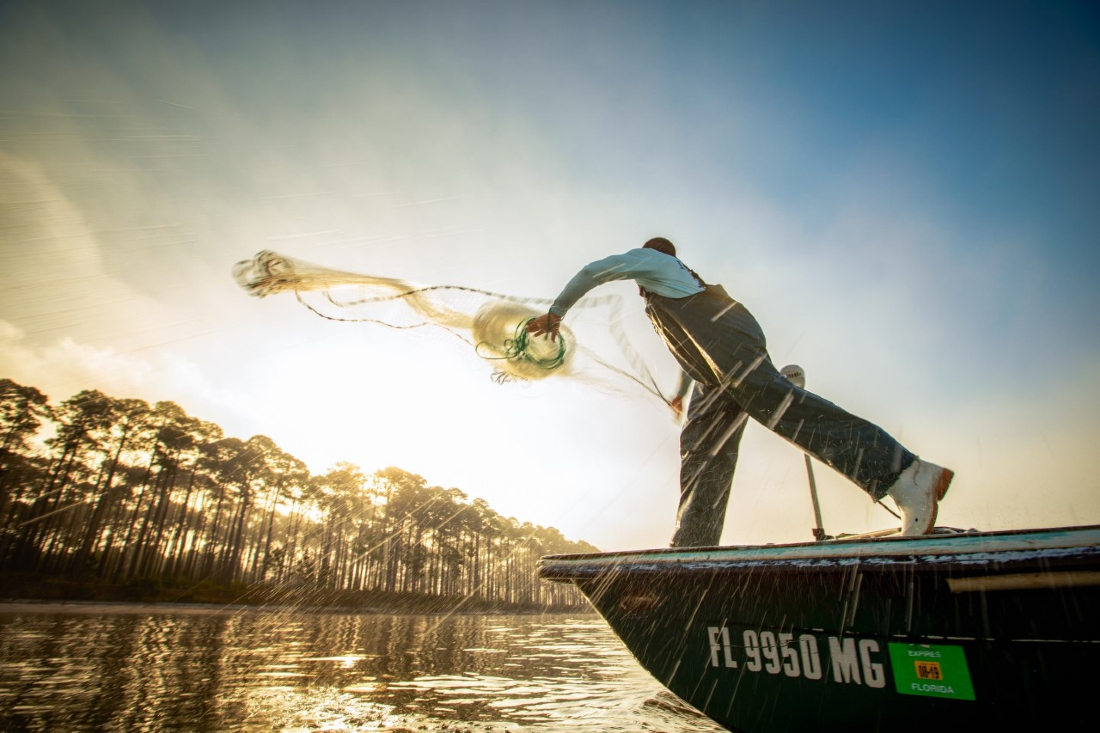 Man throwing net to catch fish