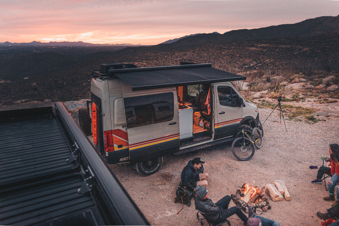 Van camper with people enjoying campfire by car.