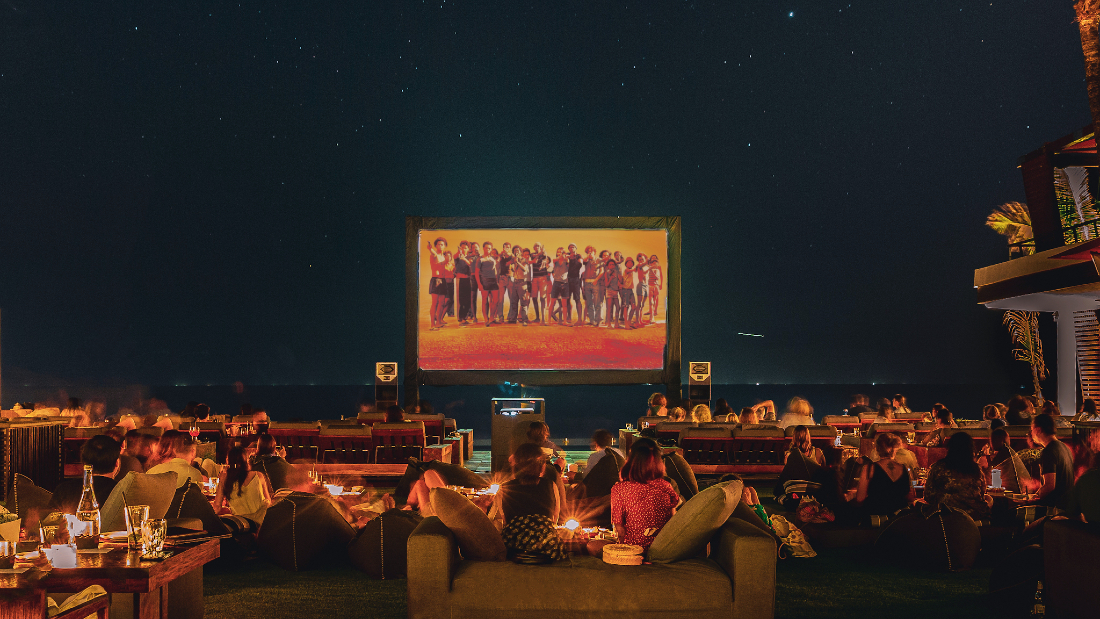 Guests enjoying a movie on the screen outside at night
